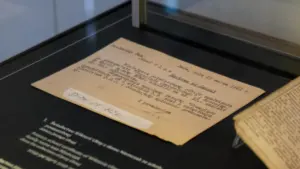 Archiwalny dokument historyczny wyeksponowany w szklanej gablocie muzealnej na czarnym tle.