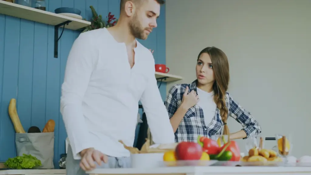 Młoda para rozmawia w kuchni podczas wspólnego przygotowywania porannego posiłku w domu.