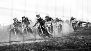 Grupa motocyklistów crossowych biorących udział w intensywnym wyścigu na torze żużlowym.