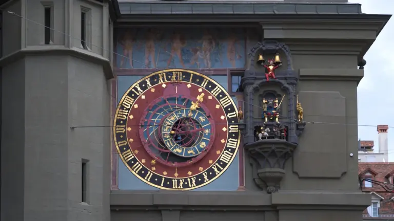 Złożony zegar astronomiczny z symbolami zodiaku na historycznej fasadzie budynku w Europie.