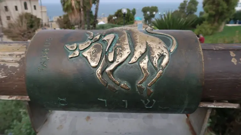 Znak zodiaku Byk odlany w brązie na cylindrycznym pomniku w parku.