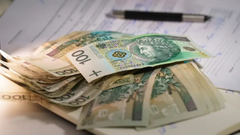 Stos polskich banknotów na dokumentach finansowych związanych z gospodarką i kredytami.