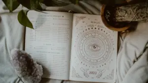 Otwarta księga astrologiczna z motywem księżyca i kryształem na łóżku