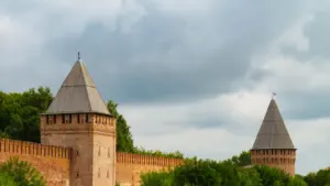 Historyczne mury obronne Smoleńska z charakterystycznymi wieżami obronnymi w słoneczny, pochmurny dzień.
